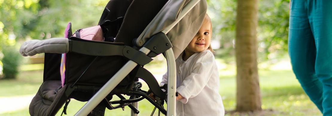 Toddler standing behind her stroller